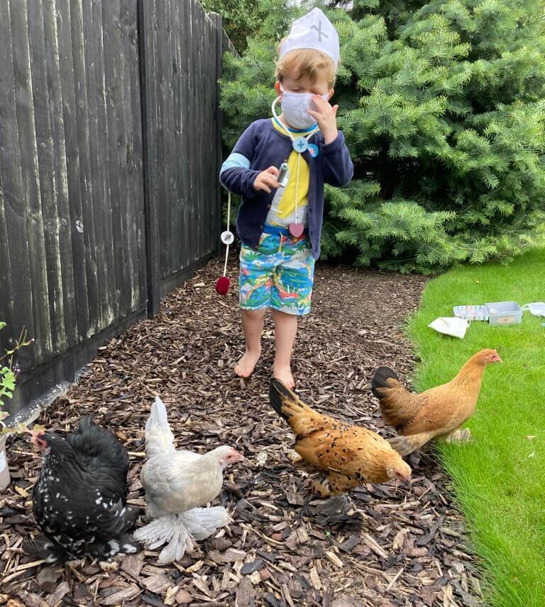 Boy dressed in surgical mask with stethoscope playing with hen patients